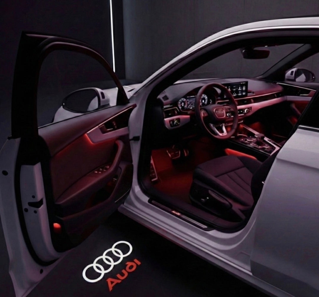 LED-instapverlichting – Stijl 1: Vier ringen met rode Audi-letters, geprojecteerd op de grond naast een geopende autodeur
